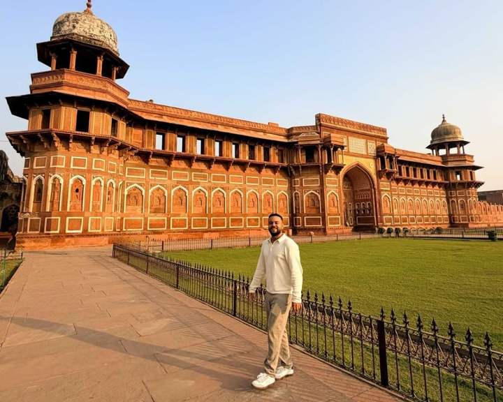 Reisender auf dem Rasen vor dem roten Sandsteinpalast Jahangiri Mahal im Fort Agra, Indien