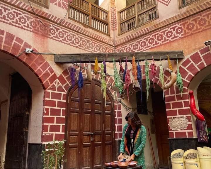 Reisende mischt Gewürze im Innenhof eines Riads mit gefärbter Wolle in Marrakesch